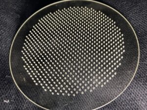ガラス旋盤と超音波加工を組み合わせ、石英プレートに微細な貫通孔を等間隔で高精度に配置した加工サンプル